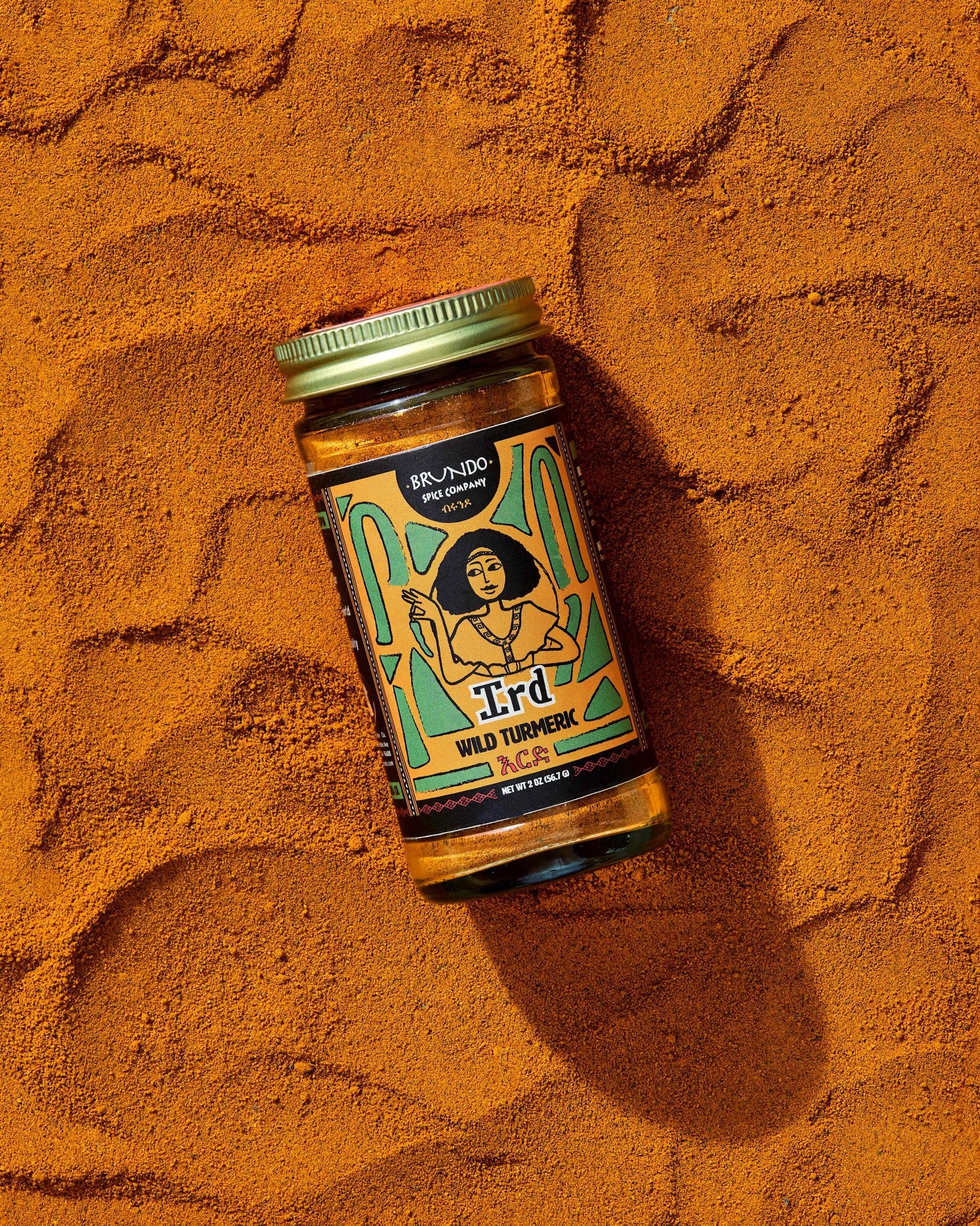 Brundo Spice Company Ird Wild Turmeric jar resting on a bed of vibrant ground turmeric.