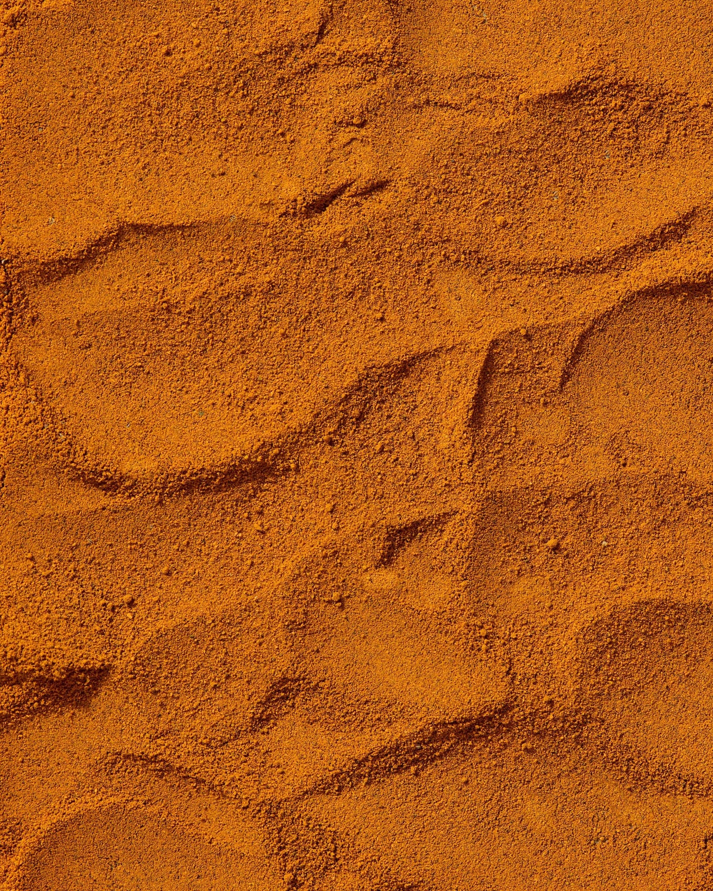 Close-up of finely ground wild turmeric powder with rich golden-orange tones.
