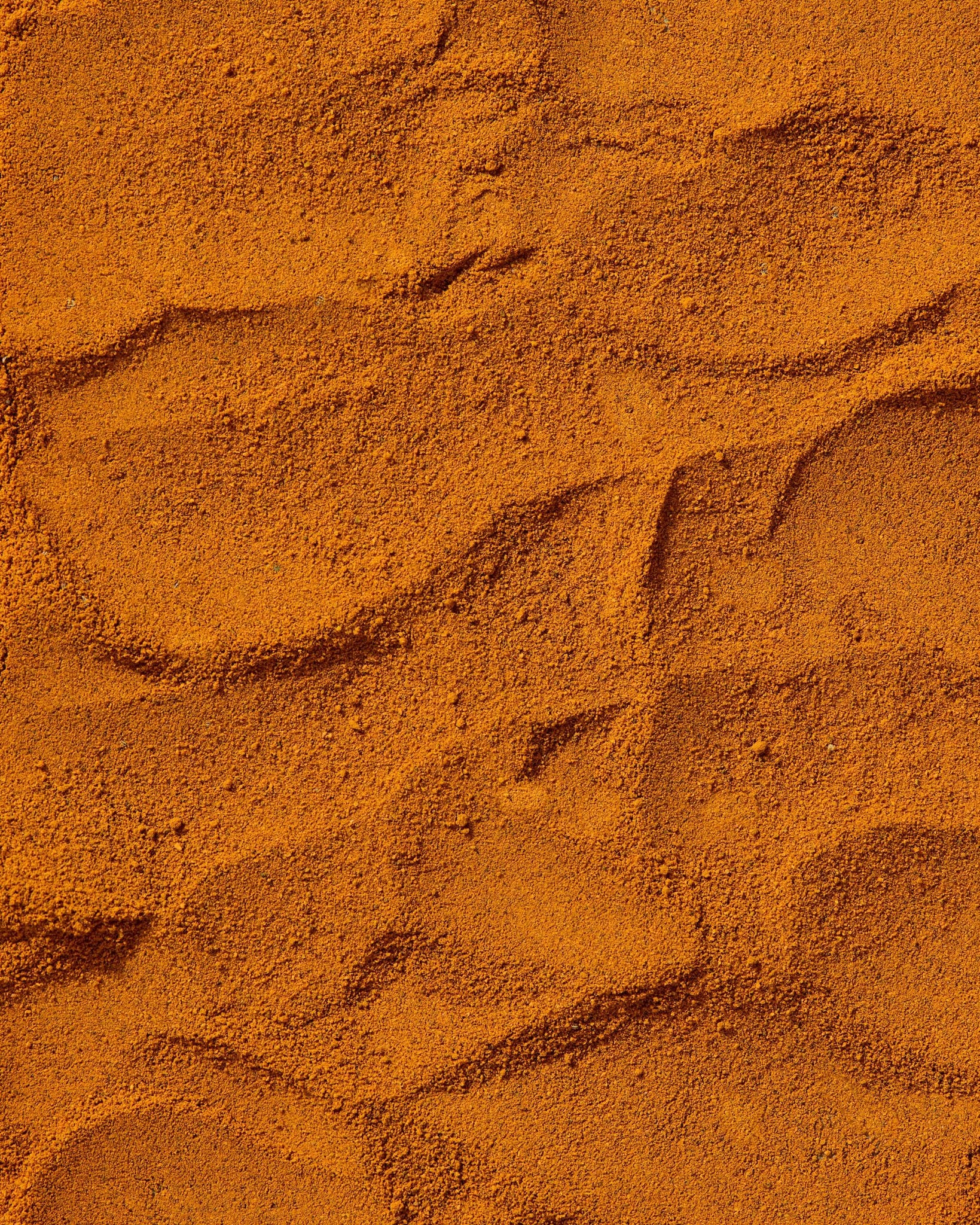 Close-up of finely ground wild turmeric powder with rich golden-orange tones.